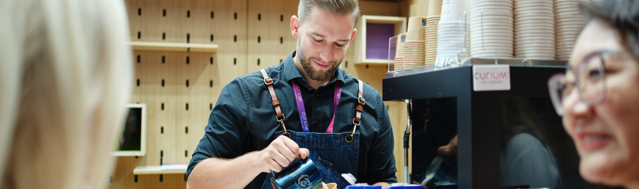 Barista gießt Milch in den Kaffee ein