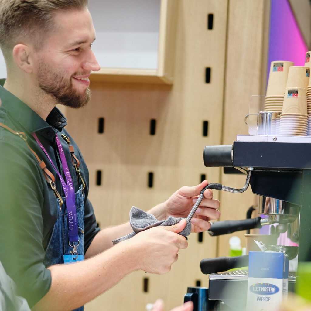 Barista steht vor einer Siebträgermaschine und extrahiert ein kaffee