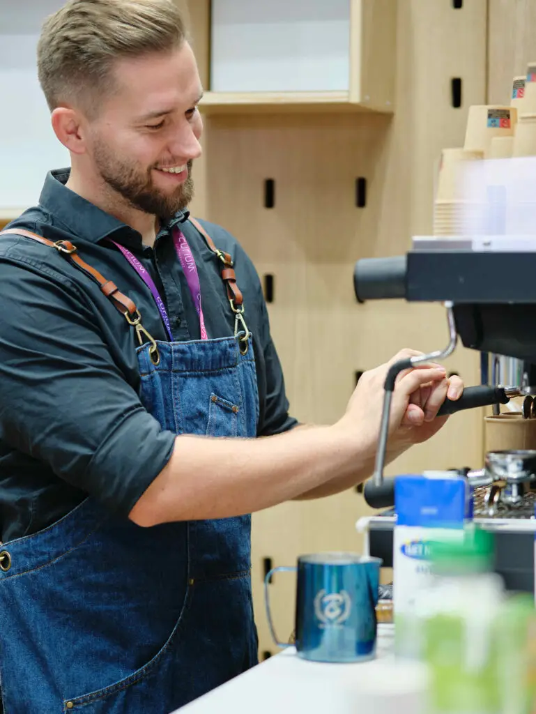 Barista steht vor einer Siebträgermaschine und extrahiert ein kaffee